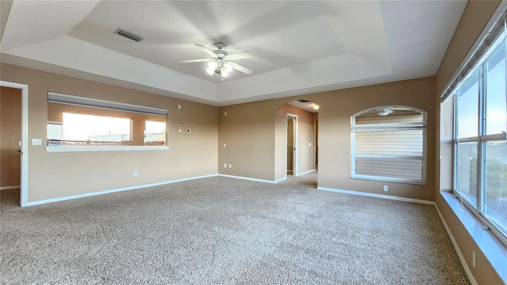 An empty living room features beige walls, tan carpeting, a tray ceiling, and large windows — 1209 APOLLO BEACH BOULEVARD, APOLLO BEACH, FL