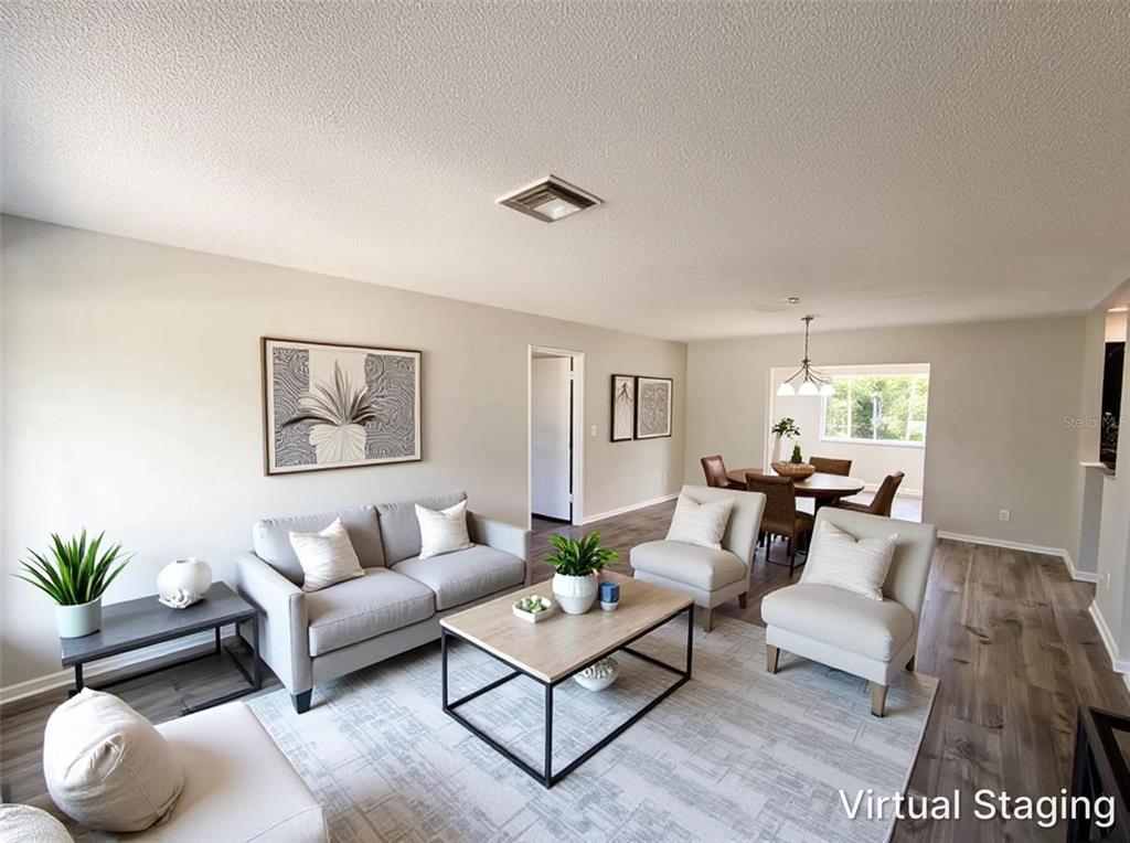 A living room with light gray walls, wood-look flooring, and virtual staging furniture — 9281 BAY DRIVE, SPRING HILL, FL