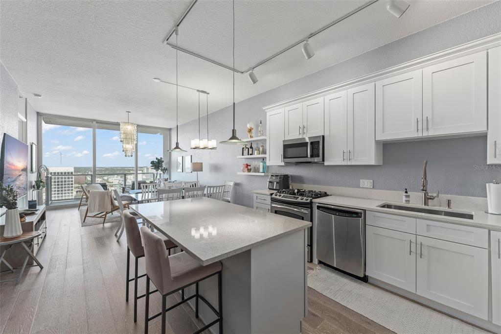 A modern kitchen with white cabinets and a quartz island opens to a living area — 150 E ROBINSON STREET UNIT 2008, ORLANDO, FL
