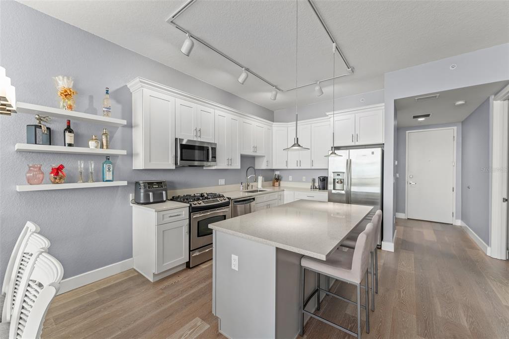 A modern kitchen features white cabinets, stainless steel appliances, a quartz island, and wood flooring — 150 E ROBINSON STREET UNIT 2008, ORLANDO, FL