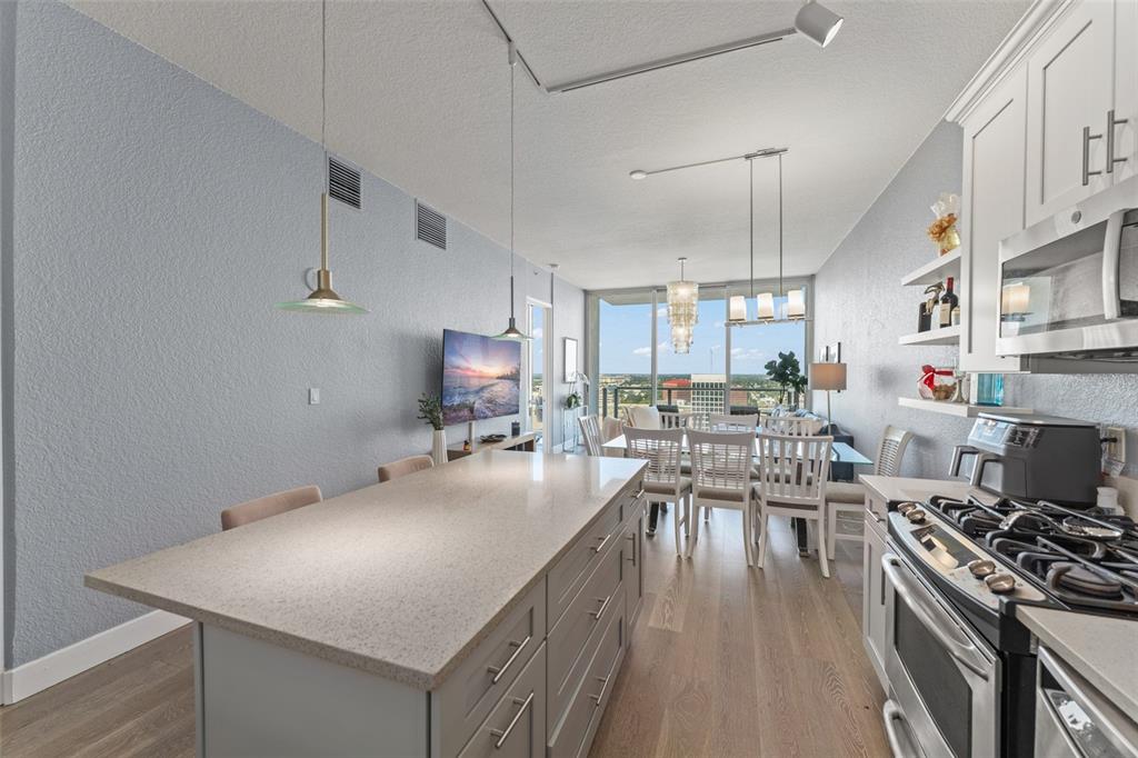 A modern kitchen with a large island overlooks a dining area and a city view — 150 E ROBINSON STREET UNIT 2008, ORLANDO, FL