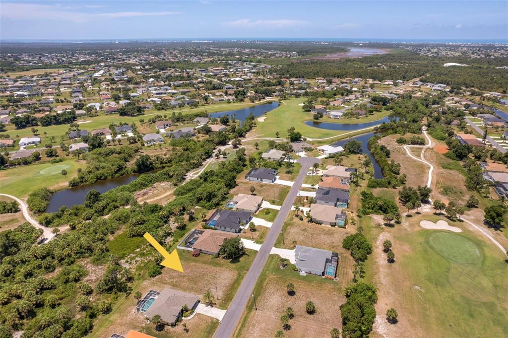An aerial view shows a vacant residential lot situated between two houses on a street — 74 LONG MEADOW COURT, ROTONDA WEST, FL