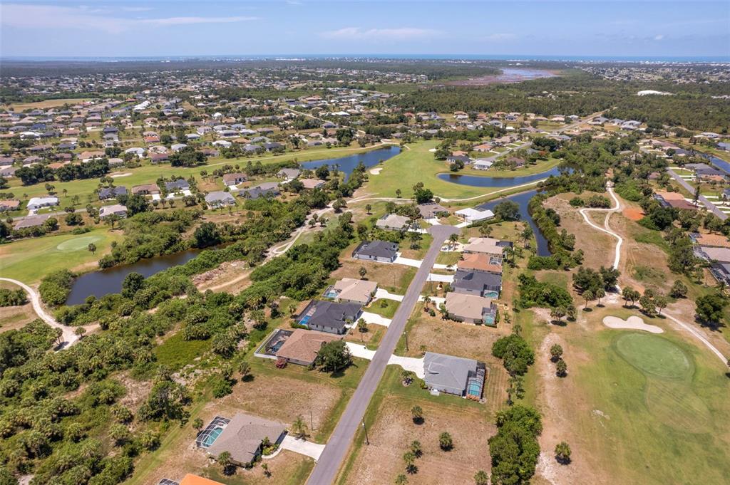 An aerial view of a suburban neighborhood featuring houses, a golf course, and ponds — 74 LONG MEADOW COURT, ROTONDA WEST, FL