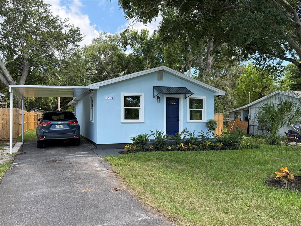 A light blue house exterior features a dark blue front door and a black awning — 3532 76TH TERRACE N, PINELLAS PARK, FL