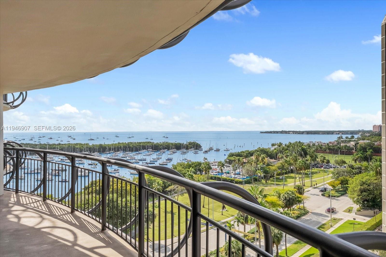 A balcony overlooks a marina, a grassy park, and the ocean under a blue sky — 2843 S Bayshore Dr # 11C, Miami FL 33133, MIAMI, FL