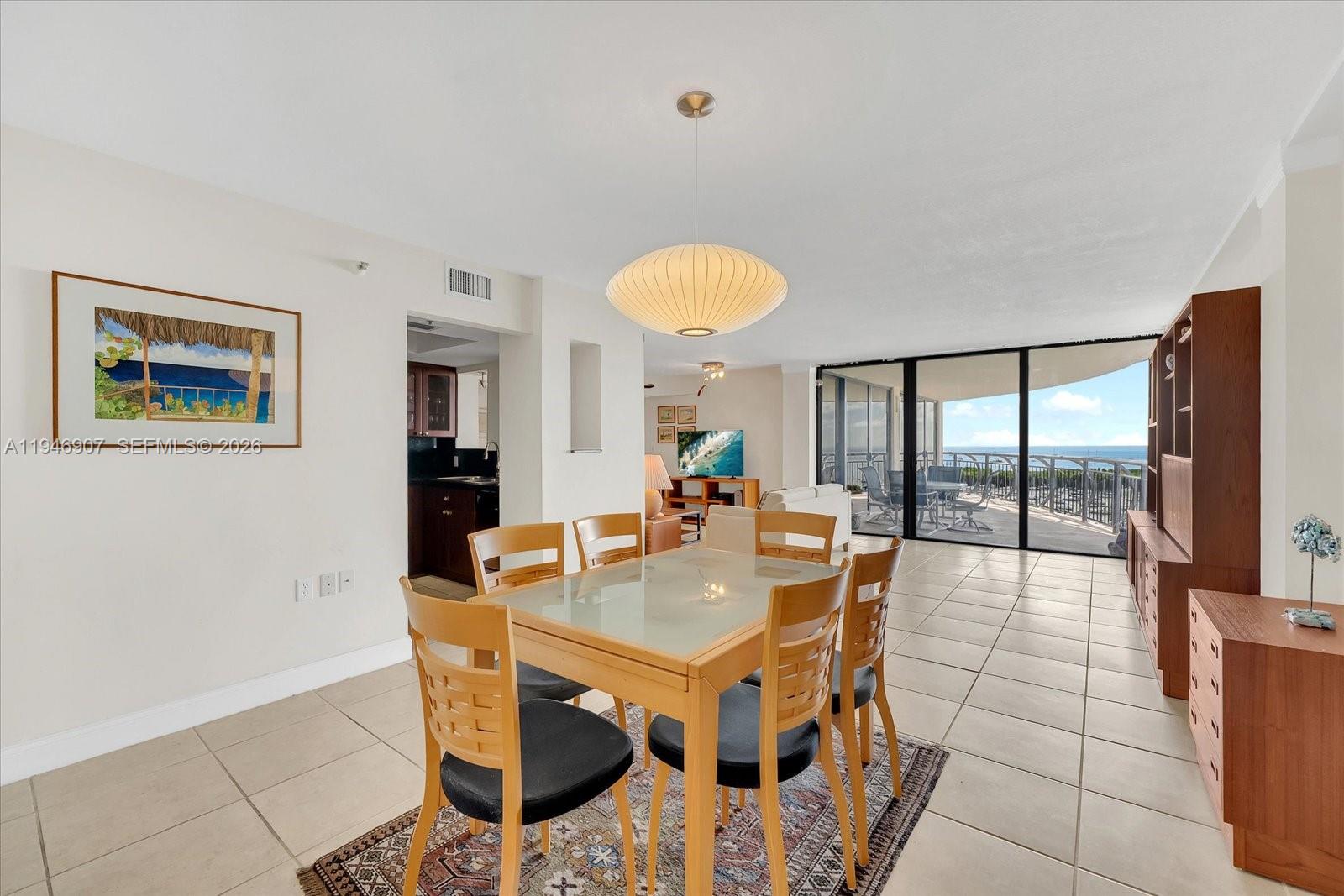 A dining area with a glass-topped table and ocean view through a sliding glass door — 2843 S Bayshore Dr # 11C, Miami FL 33133, MIAMI, FL