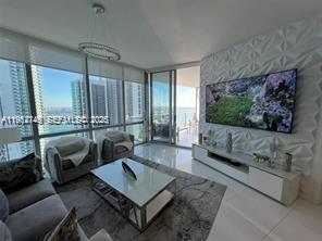 A modern living room features floor-to-ceiling windows, a textured accent wall, and a television — 851 NE 1st Ave # 3903, Miami FL 33132, MIAMI, FL
