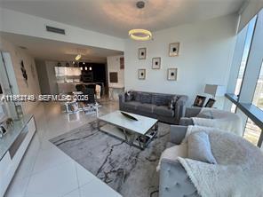 A modern living room features a grey sofa, white coffee table, and large floor-to-ceiling windows — 851 NE 1st Ave # 3903, Miami FL 33132, MIAMI, FL