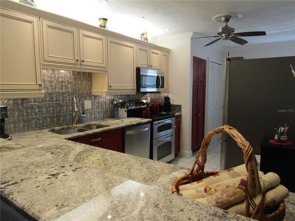 A kitchen features granite countertops, a metal tile backsplash, and two-toned cabinetry — 7351 W COUNTRY CLUB DRIVE N UNIT 202, SARASOTA, FL