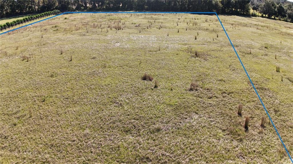 An aerial view shows a large, open grassy field outlined in blue — NW 54TH LOOP LOT 8, OCALA, FL