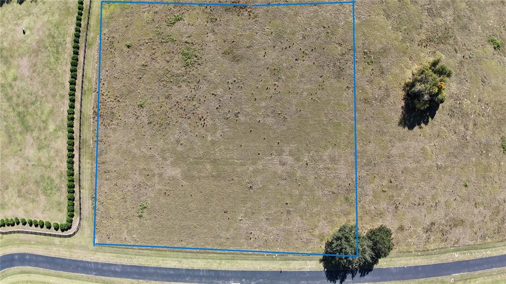 An aerial view shows a square plot of open land bordered by a paved road — NW 54TH LOOP LOT 8, OCALA, FL