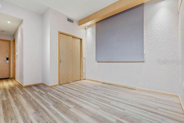 An empty room with light wood flooring, a textured wall, and a wooden closet door — 101 PALM HARBOR PARKWAY UNIT C231- B, PALM COAST, FL
