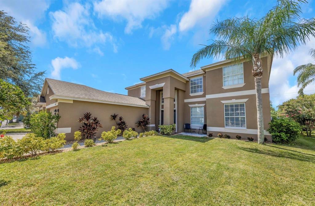 A two-story tan stucco house with a palm tree and a front lawn — 1853 PINK GUARA COURT, NEW PORT RICHEY, FL