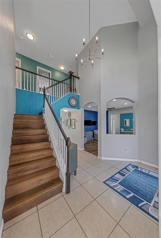 A foyer features a wooden staircase, a chandelier, and a blue accent wall — 1853 PINK GUARA COURT, NEW PORT RICHEY, FL