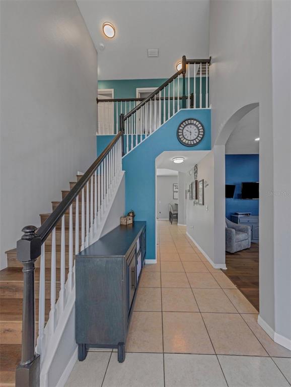 A foyer features a staircase with white railings, a blue accent wall, and tiled flooring — 1853 PINK GUARA COURT, NEW PORT RICHEY, FL