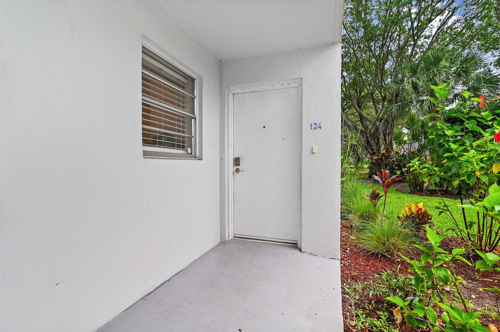 A white exterior door with the number 124 sits next to a window on a porch — 6400 NW 2nd Avenue # 124, Boca Raton FL 33487, BOCA RATON, FL