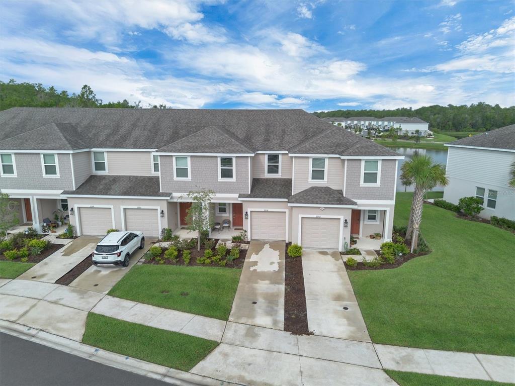 An aerial view of a multi-unit townhouse complex with attached garages and a nearby pond — 2256 PORTRAIT STREET, KISSIMMEE, FL