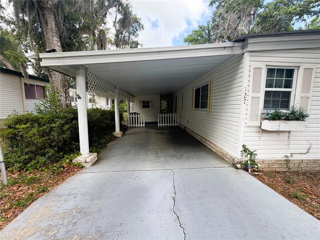 A white mobile home features a concrete carport with a white lattice screen and fence — 127 ROYAL PALM DRIVE, LEESBURG, FL