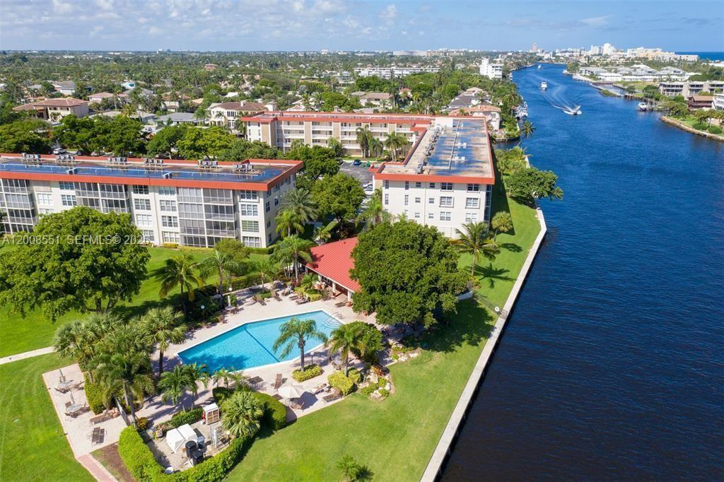 An aerial view shows two multi-story apartment buildings with a pool beside a canal — 3050 NE 48th Ct # 405, Lighthouse Point FL 33064, LIGHTHOUSE POINT, FL
