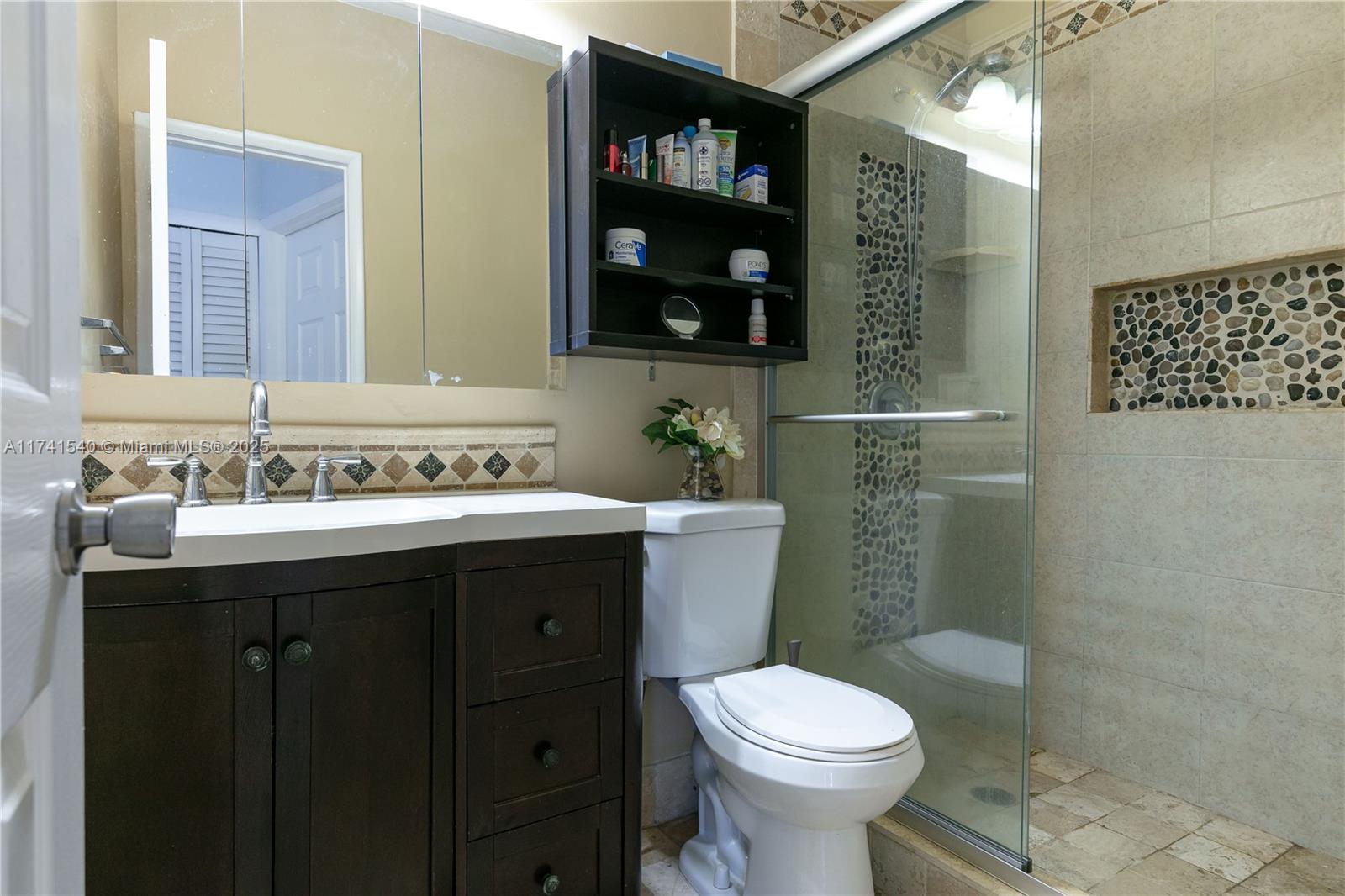 A bathroom features a dark wood vanity, a toilet, and a glass-enclosed tiled shower — 3131 S Ocean Dr # 211, Hallandale Beach FL 33009, HALLANDALE BEACH, FL