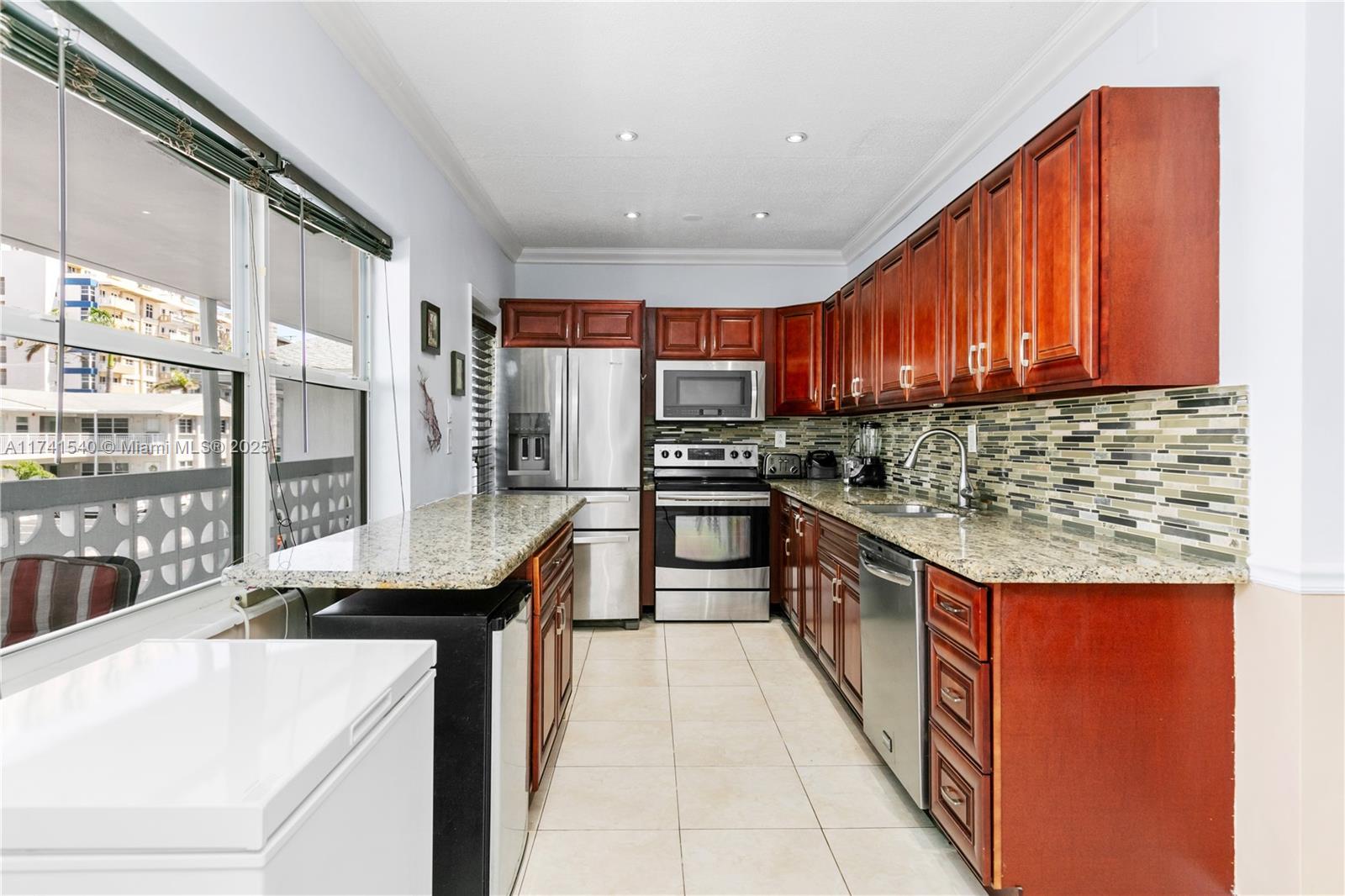 A kitchen features cherry wood cabinets, granite countertops, stainless steel appliances, and tile flooring — 3131 S Ocean Dr # 211, Hallandale Beach FL 33009, HALLANDALE BEACH, FL