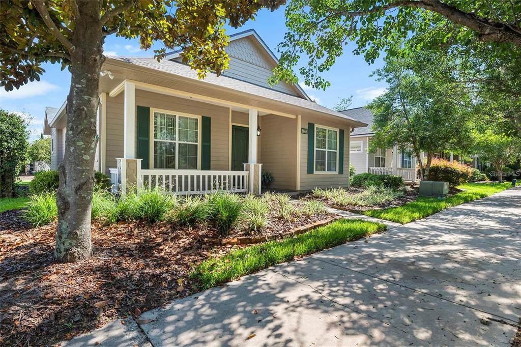 A tan single-story house with a front porch, green shutters, and a concrete driveway — 8668 SW 77TH AVENUE, GAINESVILLE, FL