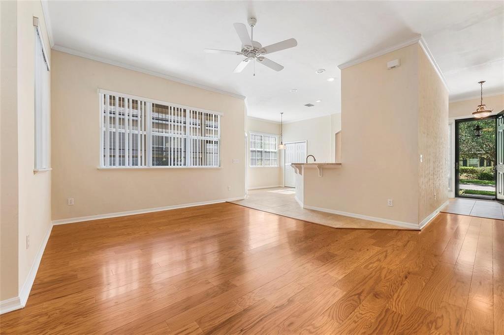 An open living room features hardwood floors, a ceiling fan, and a kitchen breakfast bar — 8668 SW 77TH AVENUE, GAINESVILLE, FL