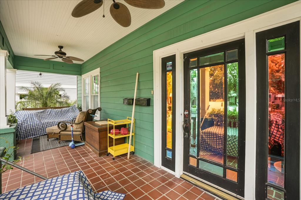 A covered front porch with green siding, tiled flooring, and a glass-paneled front door — 1629 FERRIS AVENUE, ORLANDO, FL
