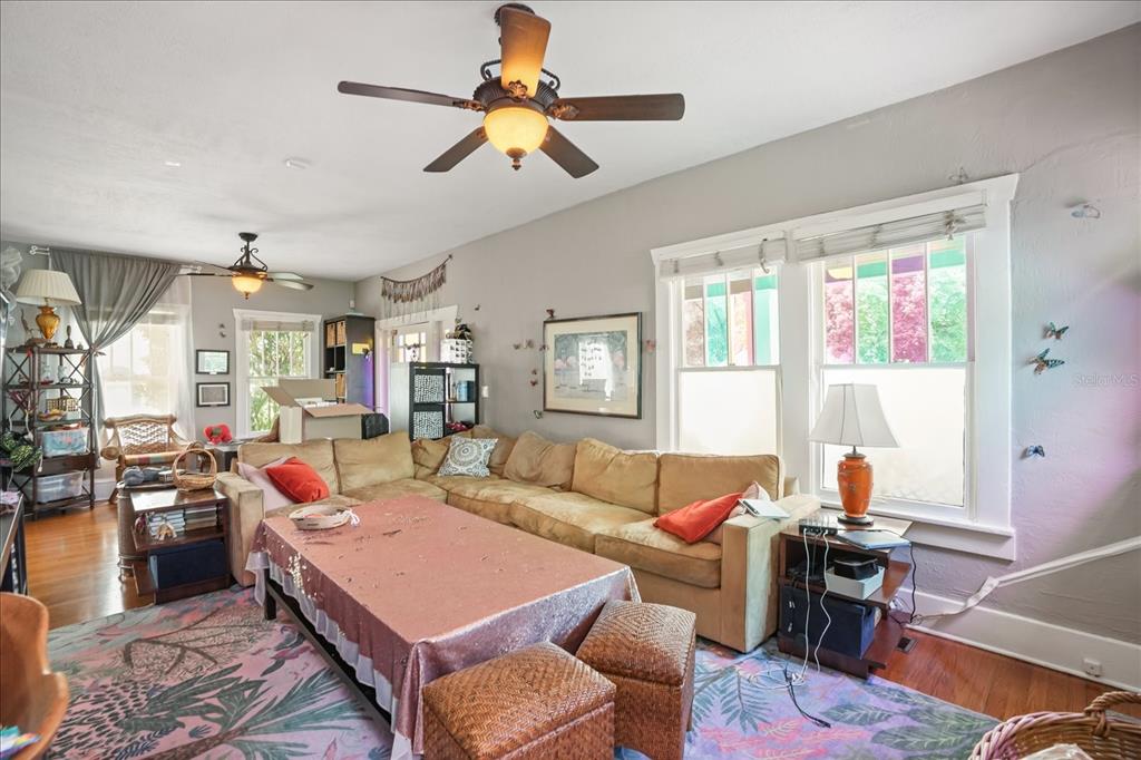 A living room features a tan sectional sofa, a pink-covered coffee table, and ceiling fans — 1629 FERRIS AVENUE, ORLANDO, FL