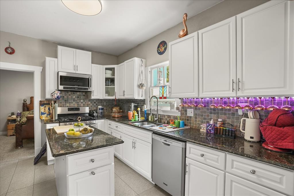 A kitchen features white cabinets, dark granite countertops, a tiled backsplash, and a center island — 1629 FERRIS AVENUE, ORLANDO, FL