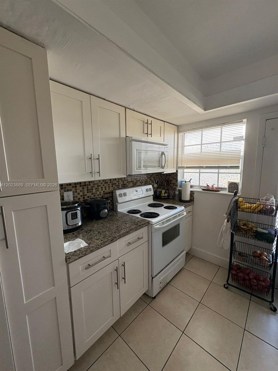 A kitchen features white cabinets, granite countertops, a white stove, and a tile floor — 11840 NE 19th Dr # 14, North Miami FL 33181, NORTH MIAMI, FL