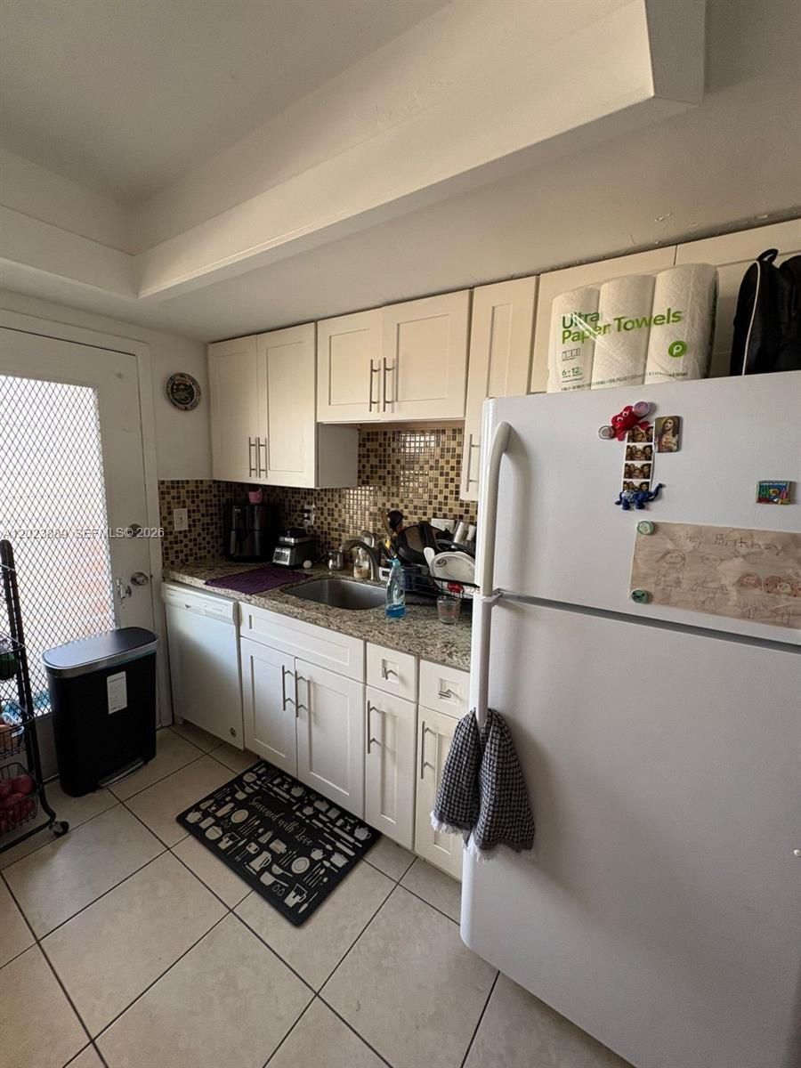 A kitchen features white cabinets, granite countertops, a tiled backsplash, and a white refrigerator — 11840 NE 19th Dr # 14, North Miami FL 33181, NORTH MIAMI, FL