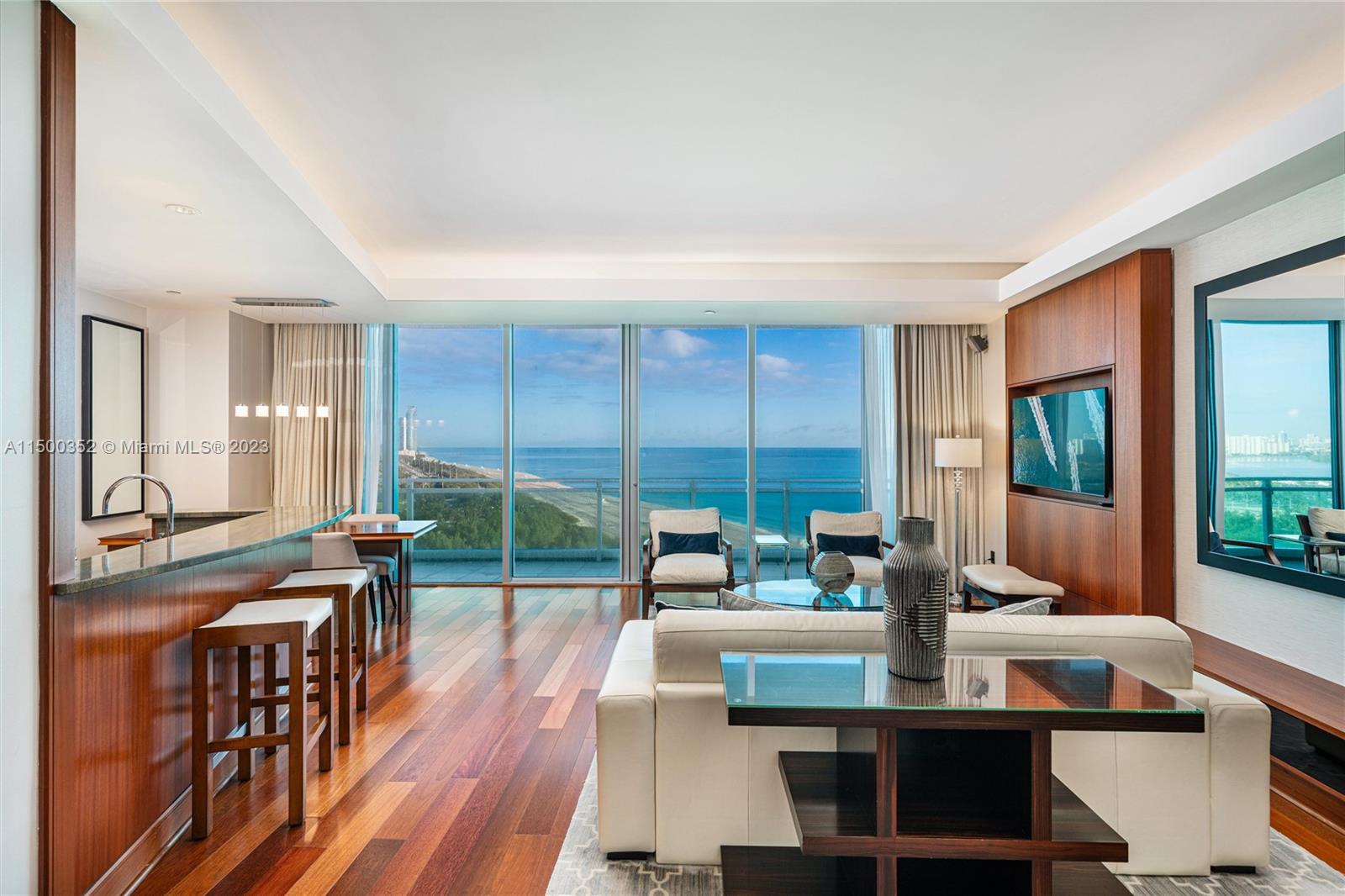 A modern living room features hardwood floors, a breakfast bar, and floor-to-ceiling ocean views — 10295 Collins Ave # 121716, Bal Harbour FL 33154, BAL HARBOUR, FL