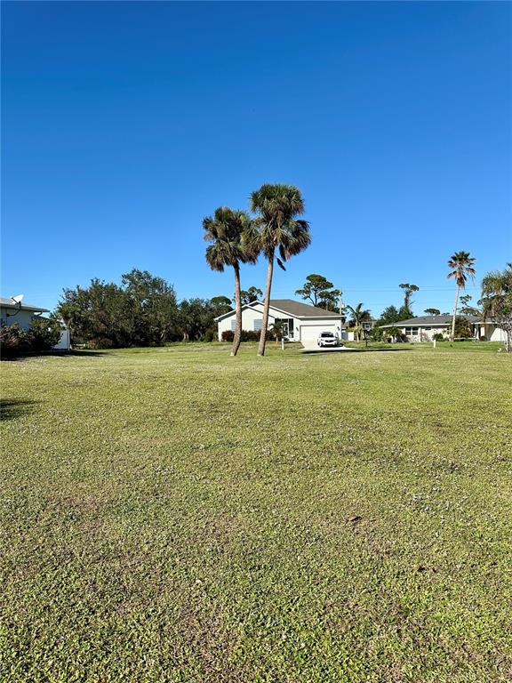 A large, grassy vacant lot sits in front of a single-story house with palm trees — 254 ANNAPOLIS LANE, ROTONDA WEST, FL