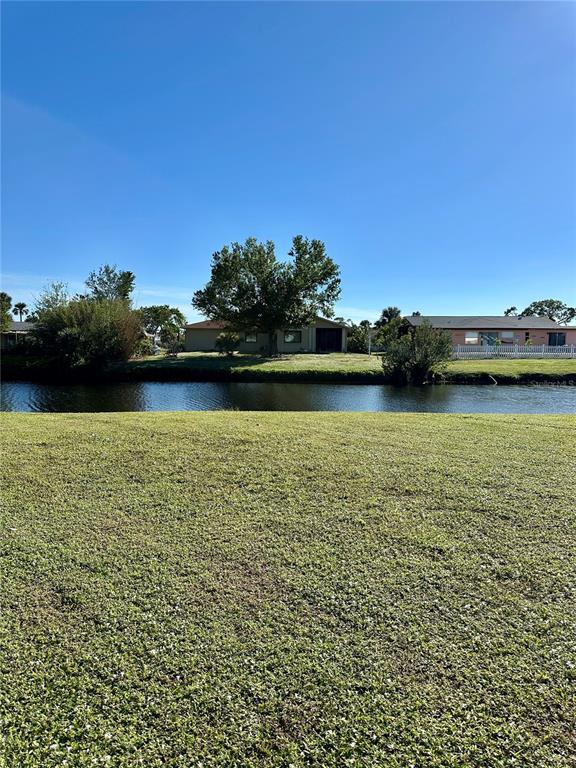 A grassy lawn overlooks a narrow canal with houses and trees in the background — 254 ANNAPOLIS LANE, ROTONDA WEST, FL