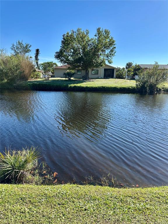 A single-story house sits across a canal with a large tree in the yard — 254 ANNAPOLIS LANE, ROTONDA WEST, FL