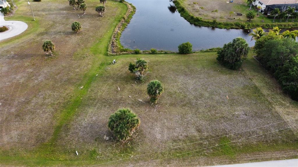 An aerial view shows a vacant, grassy residential lot bordering a small pond — 23999 CEDAR RAPIDS ROAD, PUNTA GORDA, FL