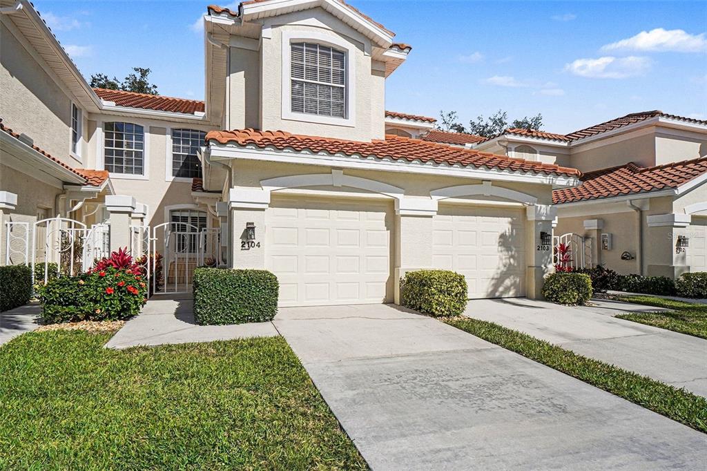 A two-story townhouse with a two-car garage, stucco exterior, and a red tile roof — 11270 JACANA COURT UNIT 2104, FORT MYERS, FL