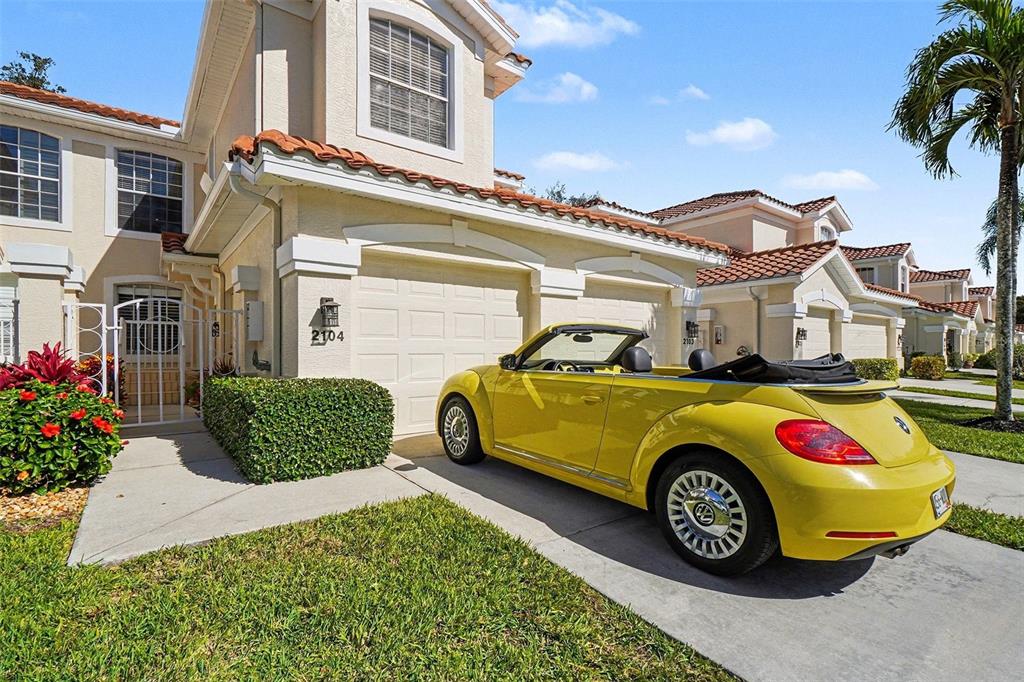 A yellow convertible Volkswagen Beetle is parked in the driveway of a two-story suburban home — 11270 JACANA COURT UNIT 2104, FORT MYERS, FL