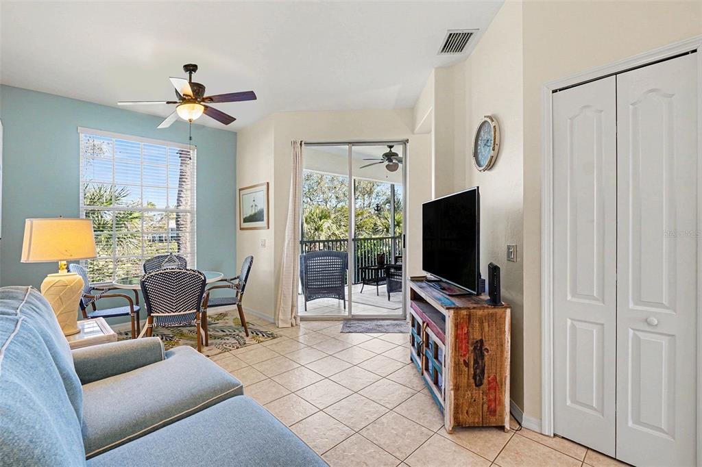 A living and dining area with tile floors, a ceiling fan, and a sliding glass door — 11270 JACANA COURT UNIT 2104, FORT MYERS, FL