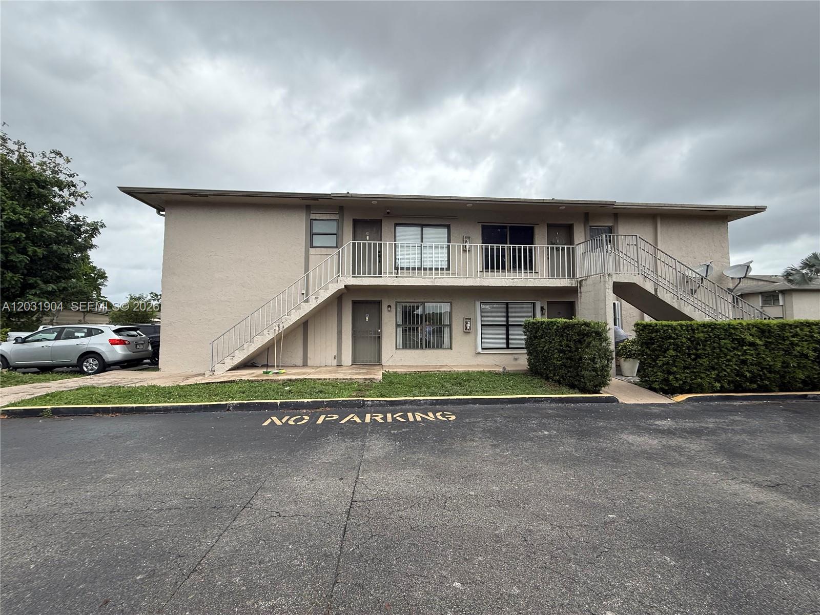 A two-story apartment building features exterior staircases, a balcony, and a paved parking area — 15316 SW 72nd St # 14, Miami FL 33193, MIAMI, FL