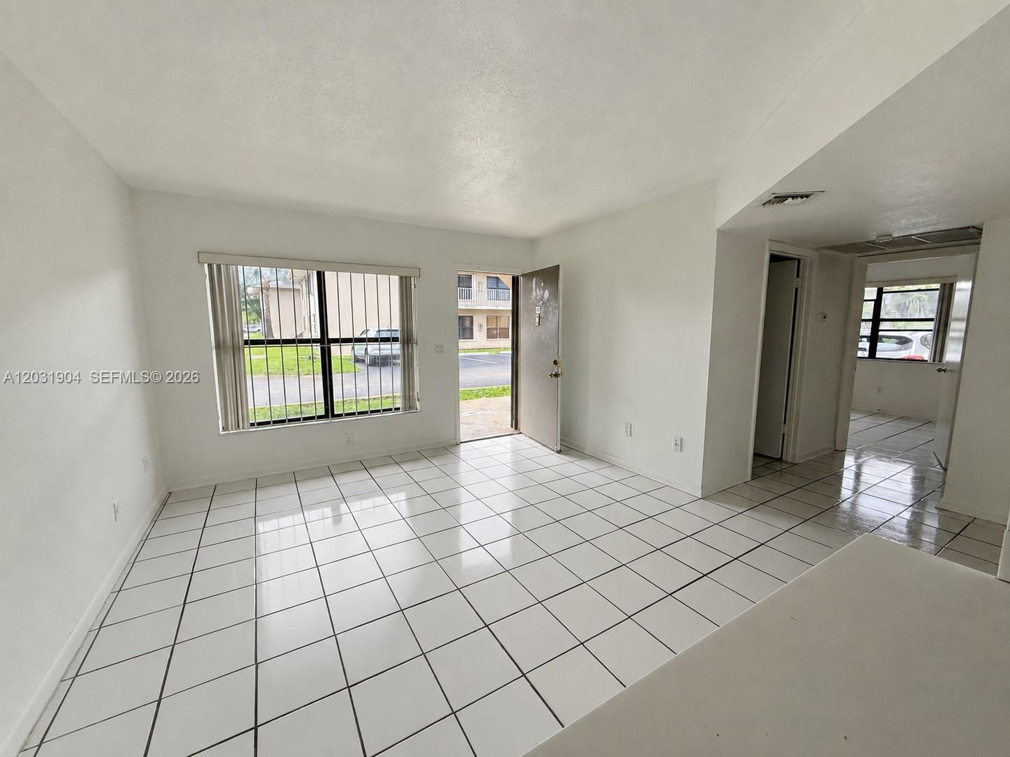 A bright living room features white tile floors, white walls, and a large window — 15316 SW 72nd St # 14, Miami FL 33193, MIAMI, FL