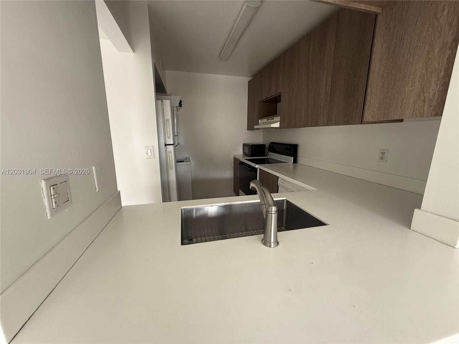 A kitchen features white countertops, a stainless steel sink, and wood-toned upper cabinets — 15316 SW 72nd St # 14, Miami FL 33193, MIAMI, FL