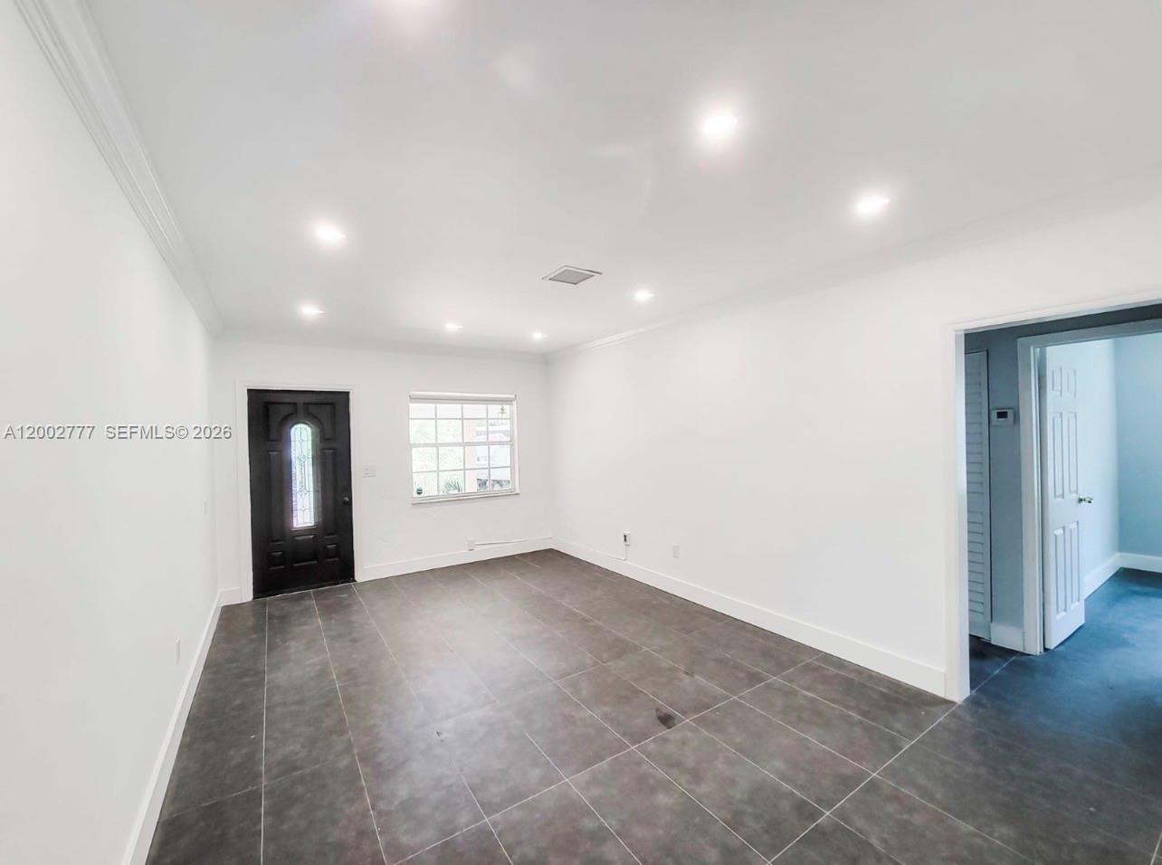 A bright room features white walls, recessed lighting, and dark gray tiled flooring — 3685 SW 1st Ave, Miami FL 33145, MIAMI, FL