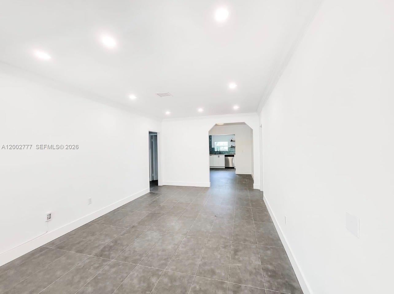 A bright, empty room features gray tile flooring, white walls, and recessed ceiling lighting — 3685 SW 1st Ave, Miami FL 33145, MIAMI, FL