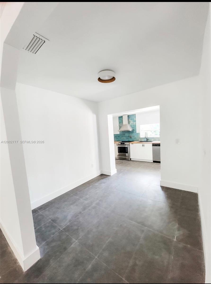 A dining area with gray tile flooring leads into a kitchen with blue backsplash tiles — 3685 SW 1st Ave, Miami FL 33145, MIAMI, FL