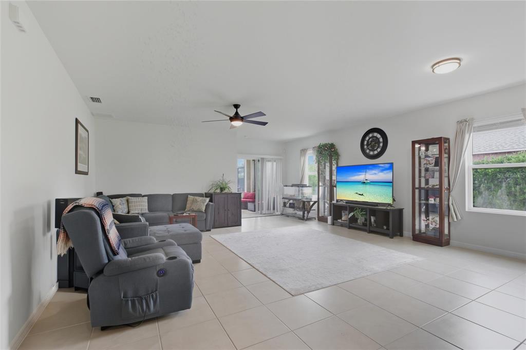 A living room with tile flooring, a gray sectional, a recliner, and a television console — 314 SE VAN LOON TERRACE, CAPE CORAL, FL