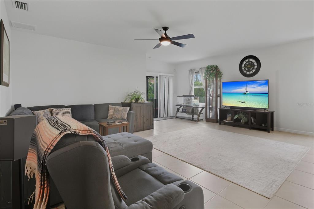 A living room features a gray sectional sofa, a television on a stand, and tile flooring — 314 SE VAN LOON TERRACE, CAPE CORAL, FL