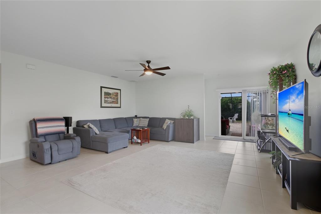 A living room features a gray sectional sofa, a recliner, a television, and sliding glass doors — 314 SE VAN LOON TERRACE, CAPE CORAL, FL
