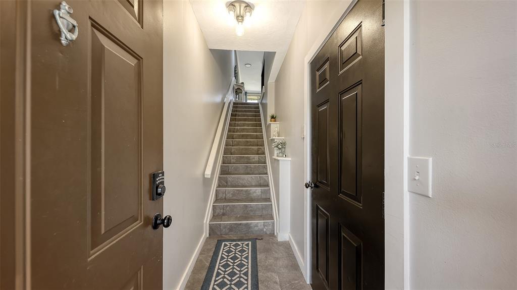 An entryway features a tiled staircase, a dark door, and a patterned floor runner — 5655 BENTGRASS DRIVE UNIT 9-116, SARASOTA, FL